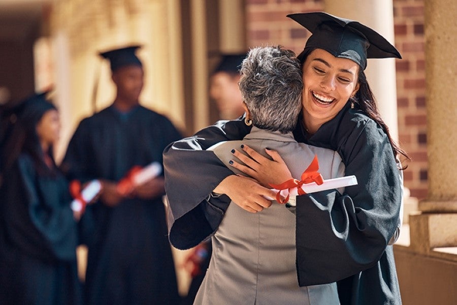 Graduate hugs parent after Hawk commencement