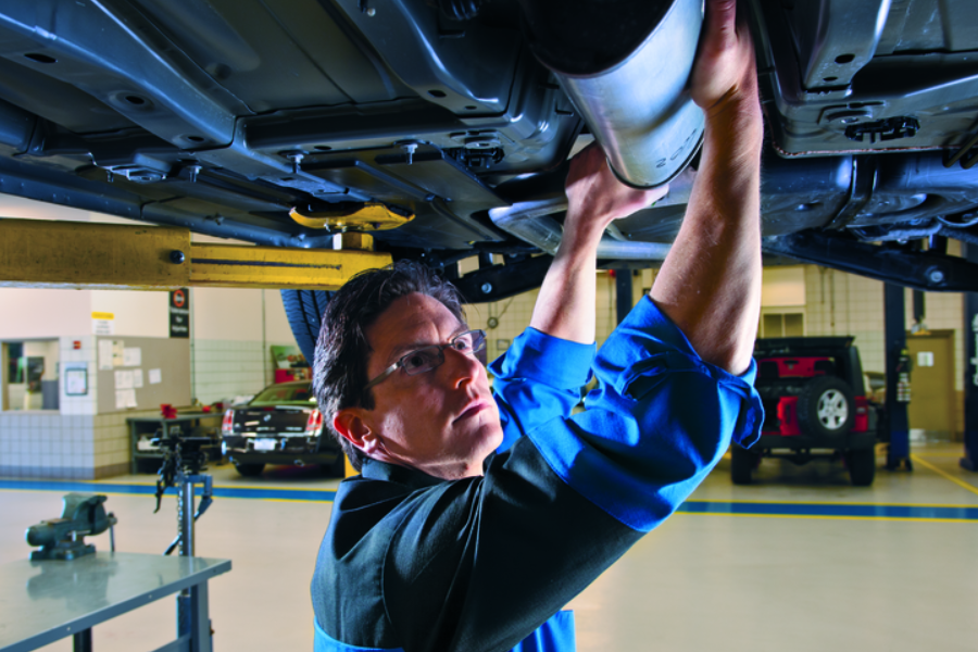Technician working underneath a lifted car at a service center
